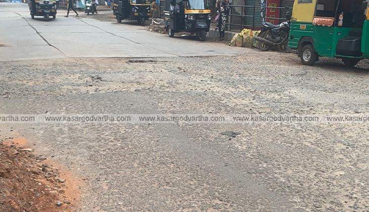 Severely damaged road with large potholes in Kasaragod city.