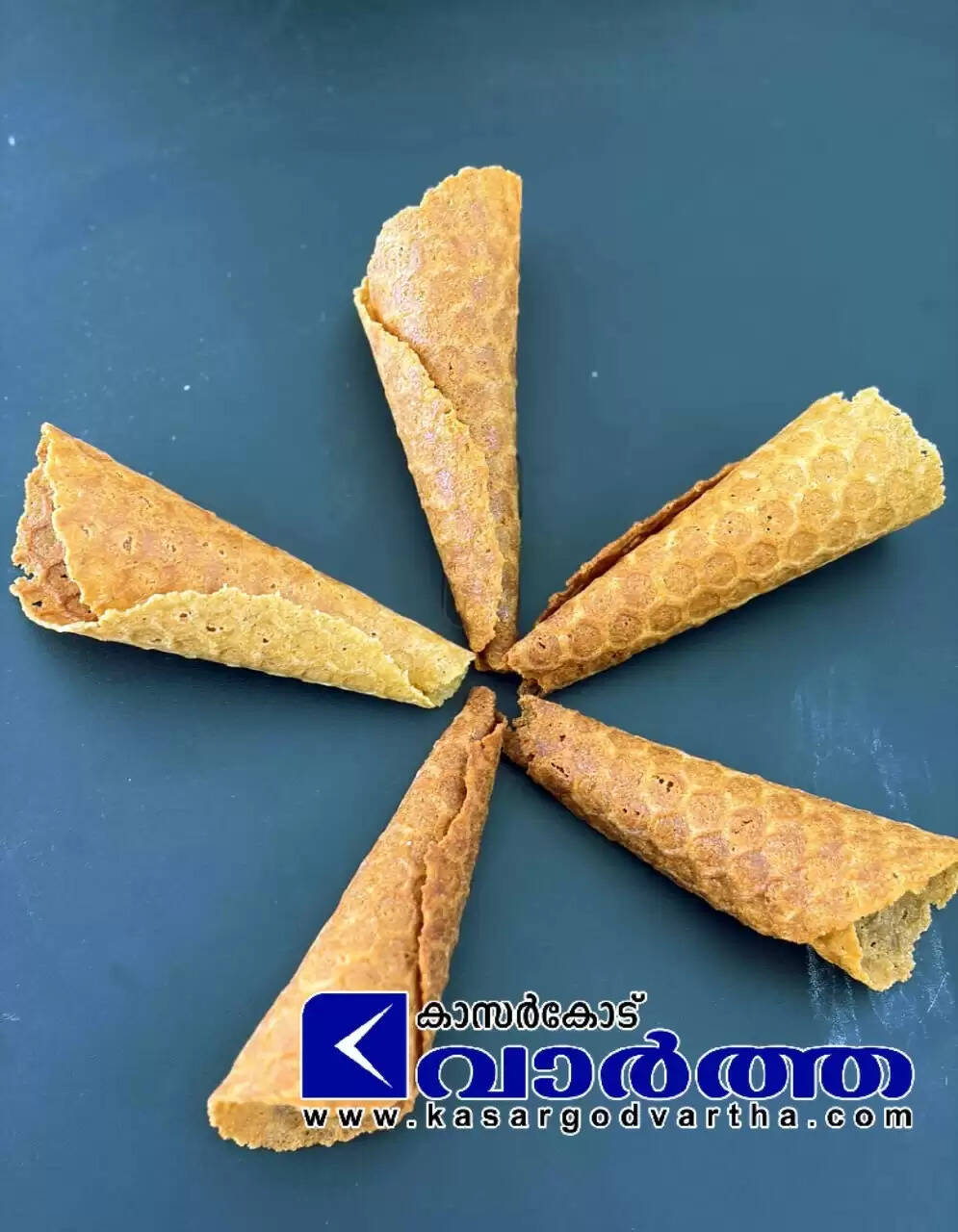 Five golden-brown waffle cones arranged in a star pattern on a dark surface.