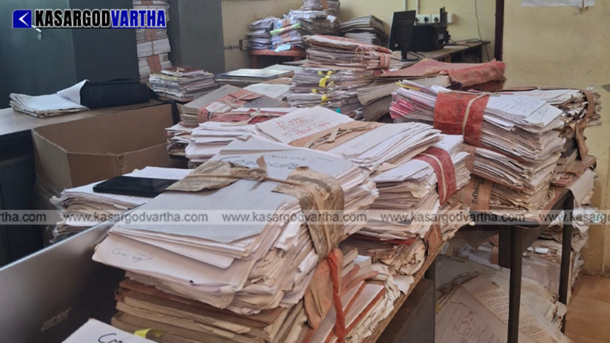 Stacks of files in a Kerala government office representing pending land conversion cases.