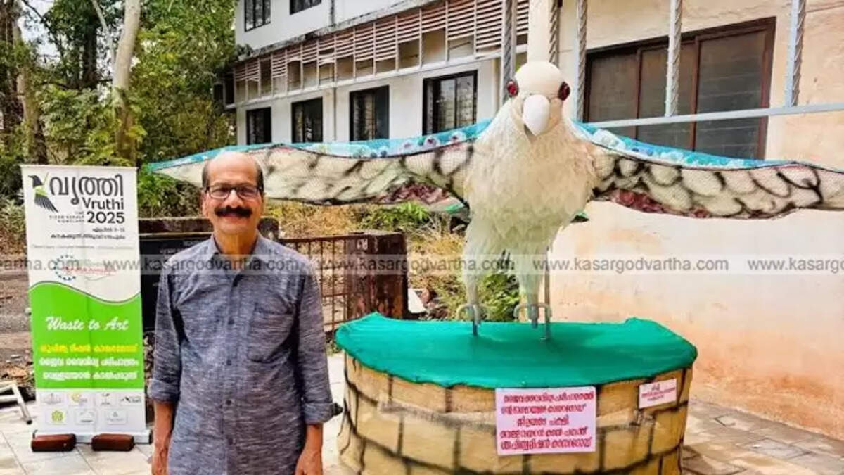 A majestic white-bellied sea eagle sculpture with outstretched wings, created from recycled materials, standing beside its artist, A.G. Narayanan.