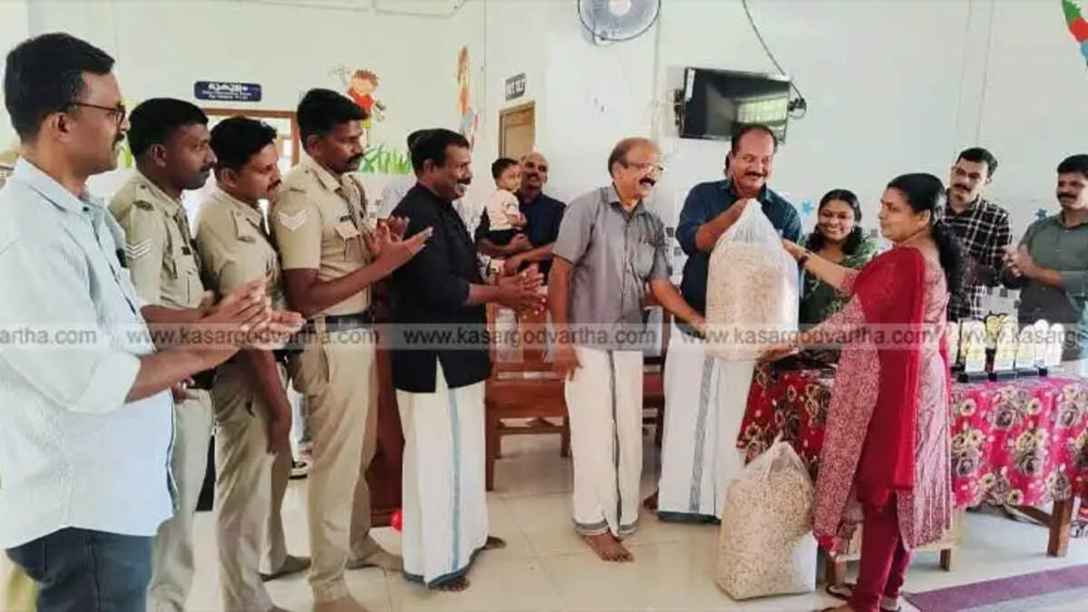 Grama Panchayat President Ajith hands over paddy Avil to school principal K.V. Sunitha as part of the harvest season distribution.