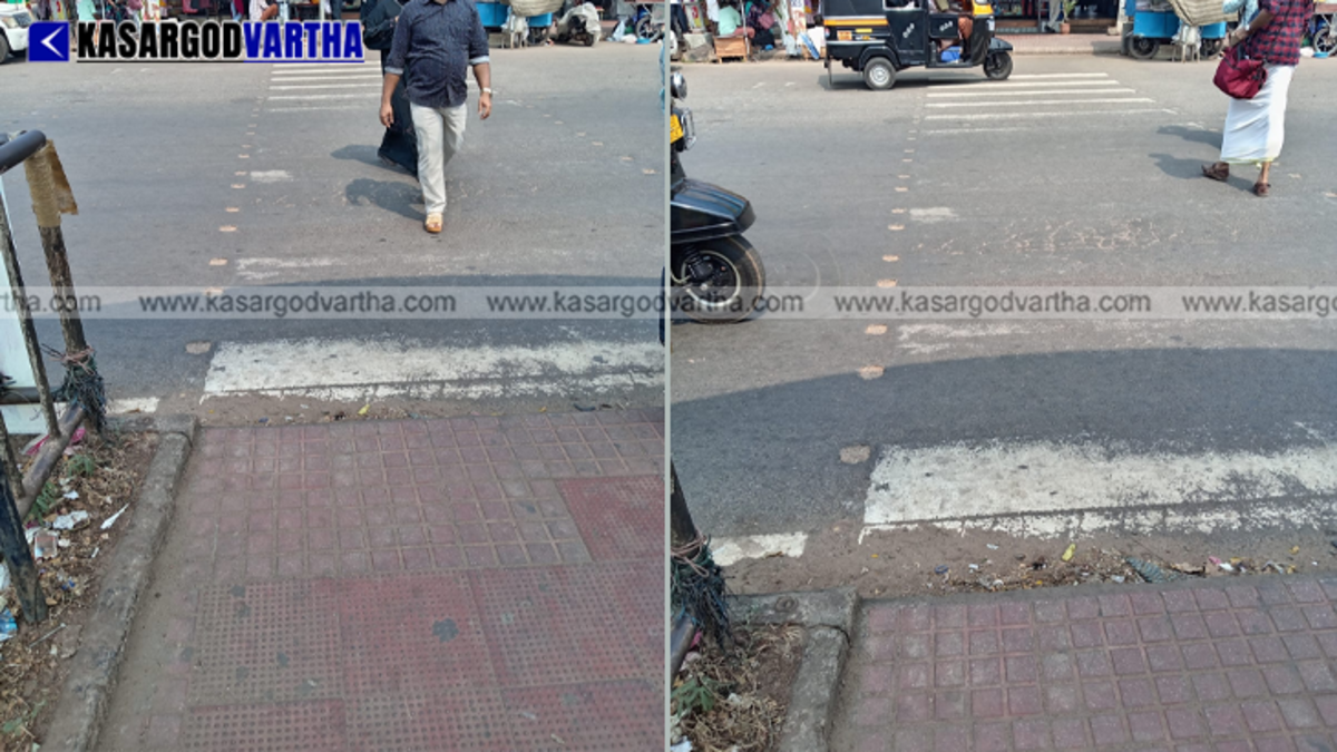 A faded zebra crossing in a busy street of Kanhangad town with moving traffic.