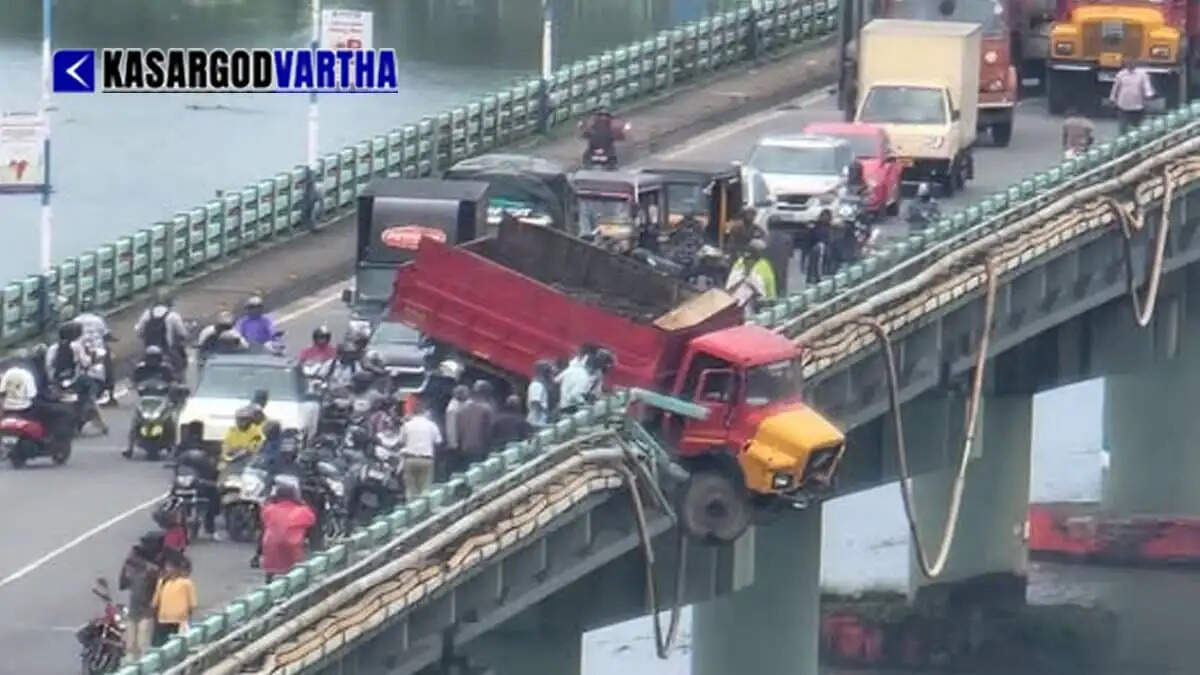 Lorry hangs precariously over lake after crashing through Thevara bridge railing in Kochi; driver escapes.