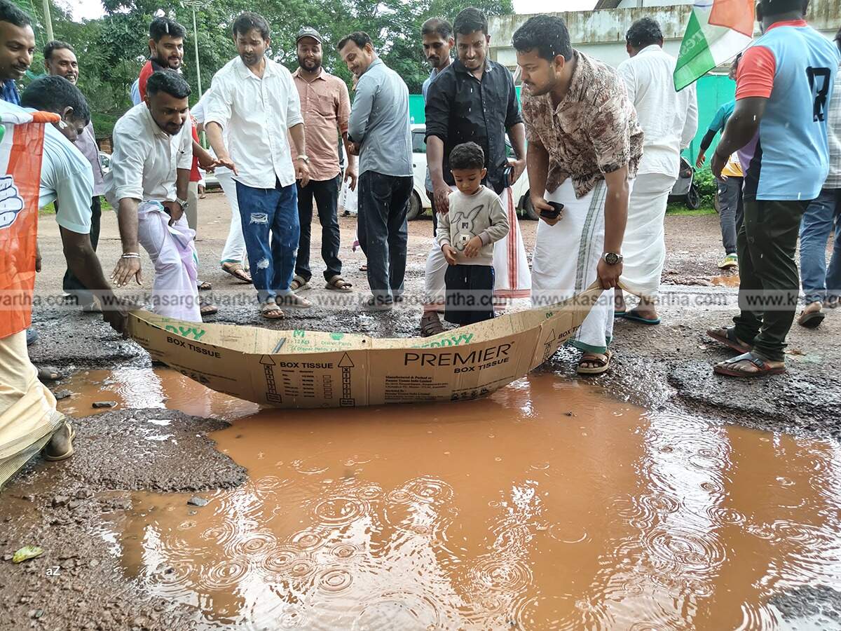 Youth Congress members protesting on a waterlogged road with a boat in Kasaragod.