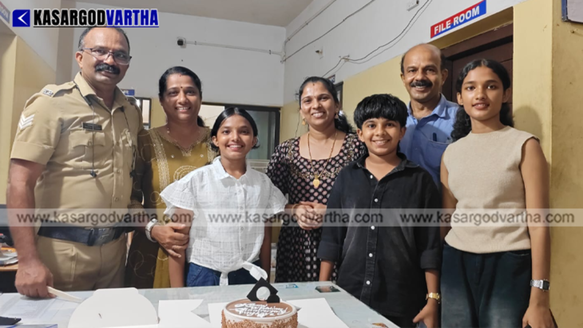 A family surprising a police officer with a cake at a police station.