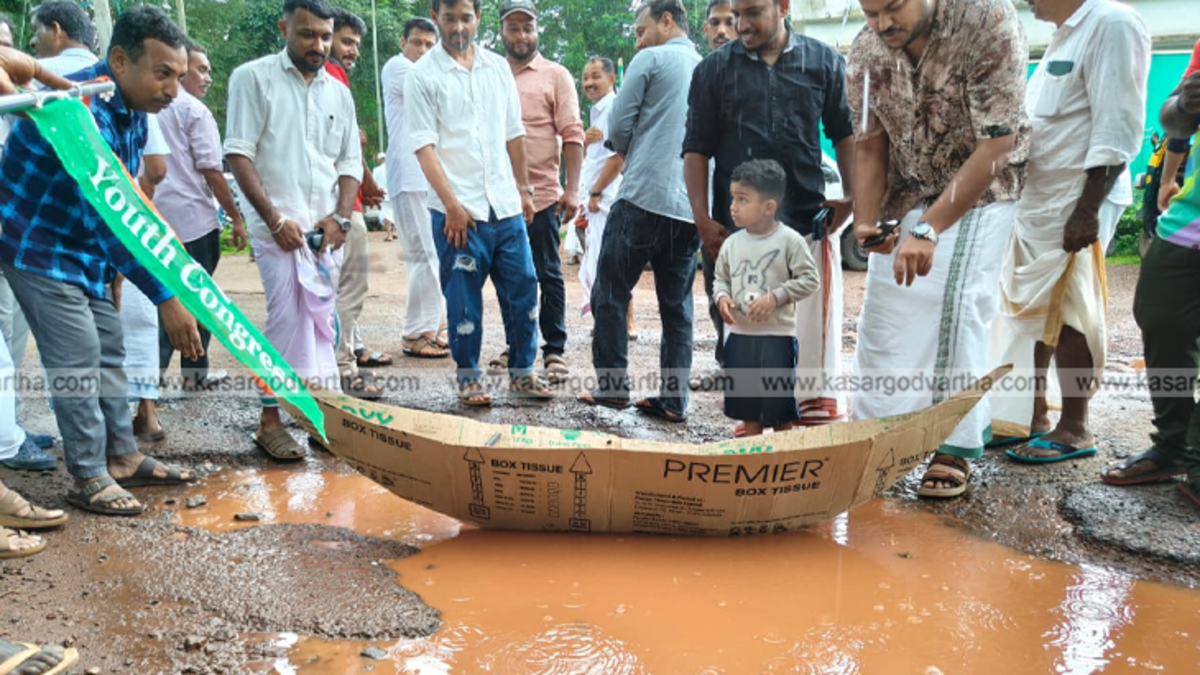 Youth Congress members protesting on a waterlogged road with a boat in Kasaragod.
