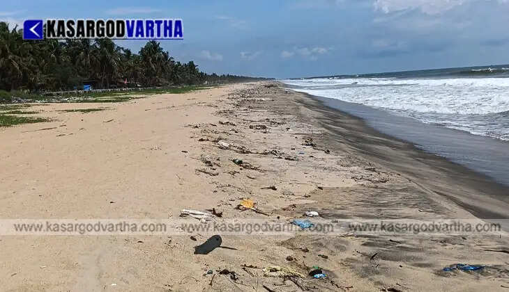 Plastic waste bottles and marine debris washed ashore on a sandy beach due to strong pre-monsoon waves.