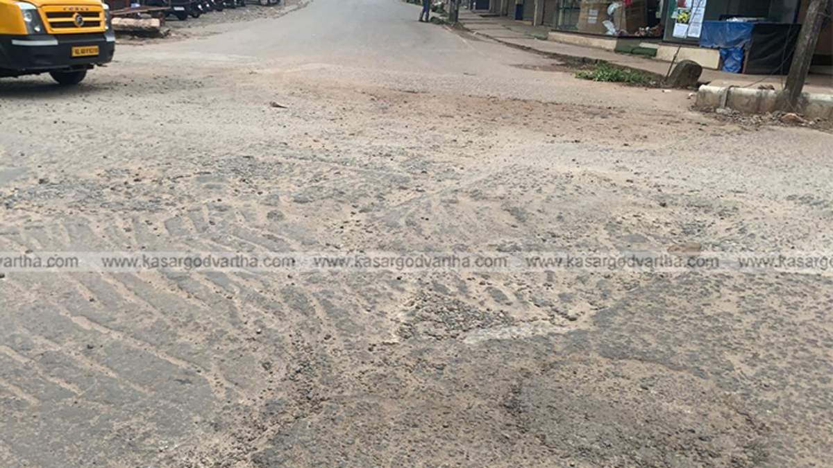 Severely damaged road with large potholes in Kasaragod city.